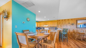 Une cuisine avec des meubles de rangement en bois, une table de salle à manger ronde et des chaises.