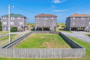 Une rangée de bâtiments à trois étages, avec un espace central recouvert d’herbe et des clôtures en bois.