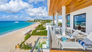 A beachside hotel with a balcony overlooking the ocean, lounge chairs, and a view of the beach and sea. - Tranquility Beach Anguilla (West End Village)