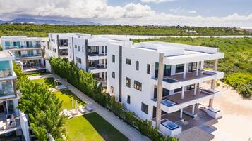 A modern multi-story residential building with balconies, a landscaped garden, and a view of the surrounding landscape.