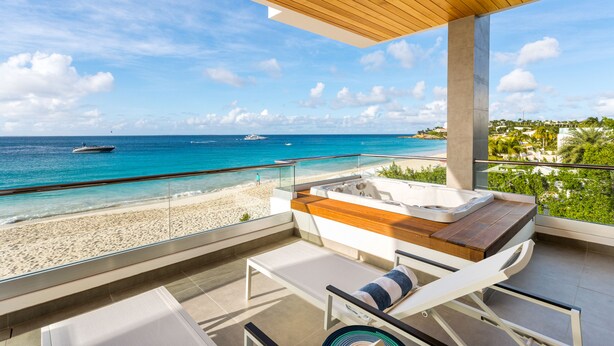 A balcony with a wooden ceiling, a hot tub, and a view of the beach and ocean. - Tranquility Beach Anguilla (West End Village)