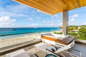 A balcony with a wooden ceiling, a hot tub, and a view of the beach and ocean. - Tranquility Beach Anguilla (West End Village)