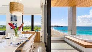A modern dining area with a view of the beach and ocean. - Tranquility Beach Anguilla (West End Village)