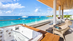 A balcony with a hot tub, wicker furniture, and a view of the ocean and yachts. - Tranquility Beach Anguilla (West End Village)