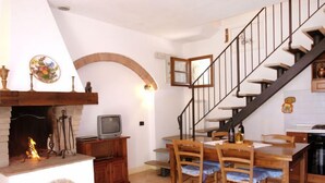 Ein Essbereich mit Kamin, Fernseher und Treppe.