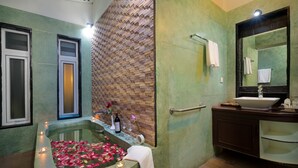 A bathroom with a large bathtub filled with rose petals, a mirror, and a sink. - De Sarann Villa (Siem Reap)