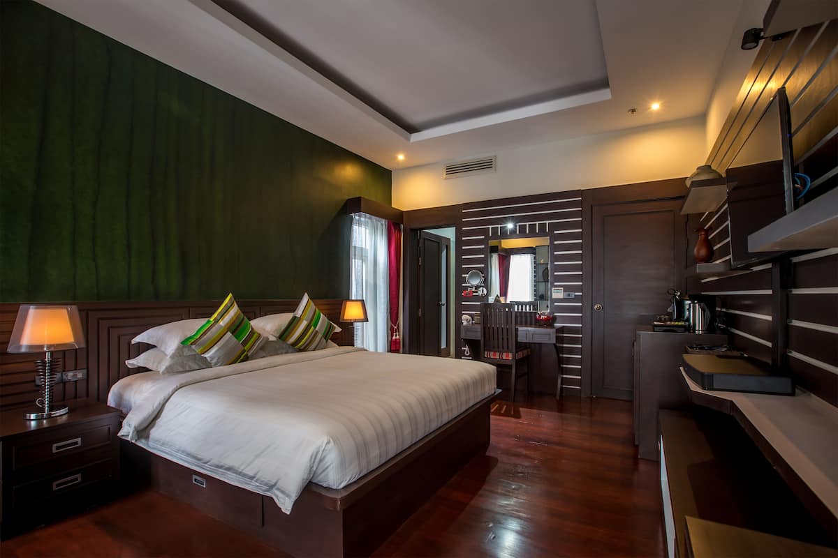 A hotel room with a large bed, a desk, and a chair.