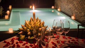 A table set for two with wine glasses, a candle, and rose petals. - De Sarann Villa (Siem Reap)