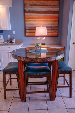 A round dining table with a dark wood finish and a glass top, accompanied by matching dark wood chairs with cushioned seats.