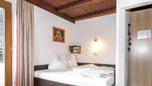 Une chambre à coucher avec un lit, un tableau, une lampe fixée au mur et un plafond en bois.