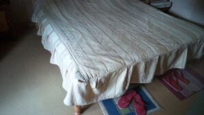 A bedroom with a bed, a chair, and a pair of slippers on the floor. - Philadelphia Retreat and Conference (Mururi)