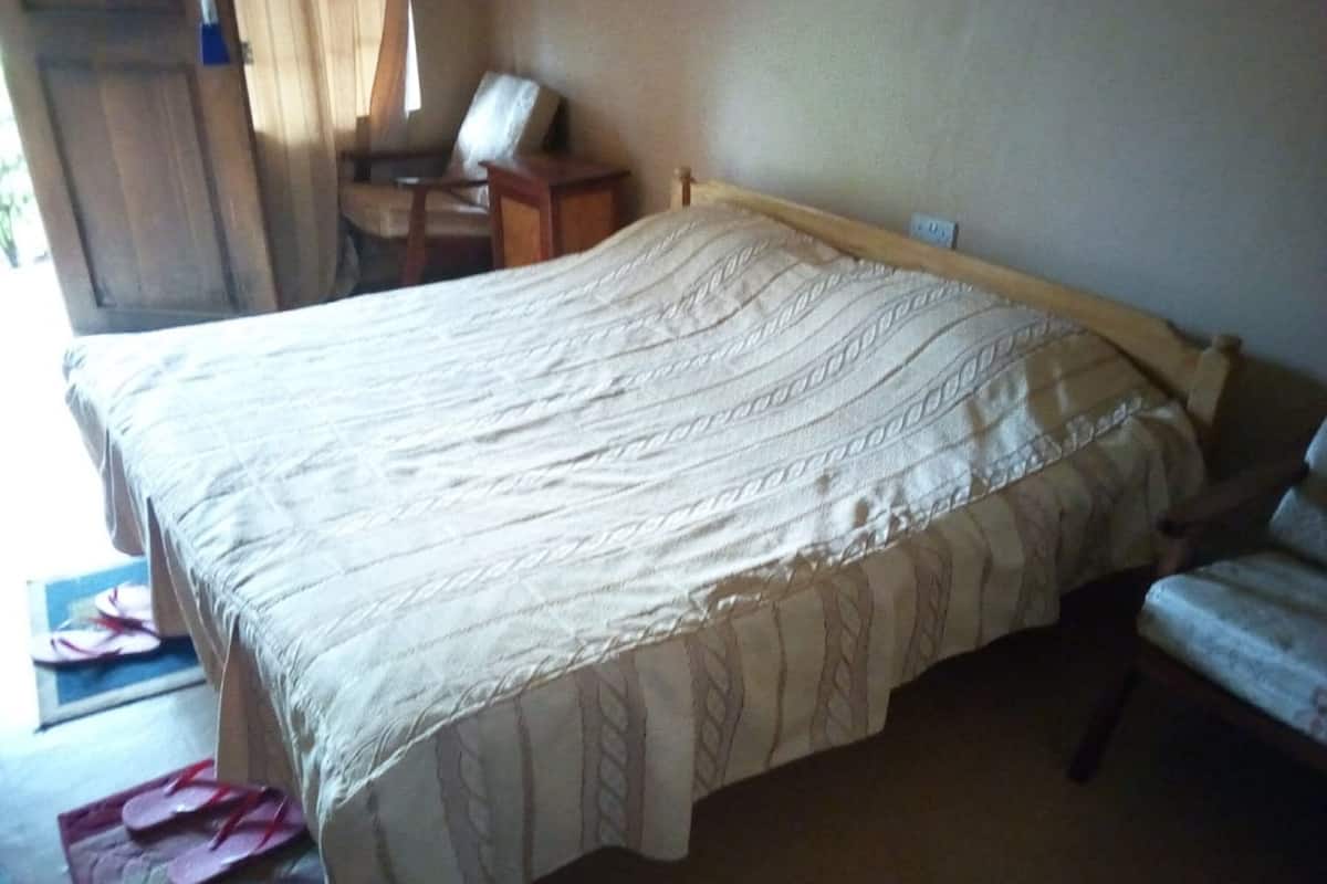 A bedroom with a bed, a chair, a desk, and a window.