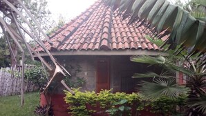A small house with a tiled roof, surrounded by lush greenery and a bamboo fence. - Philadelphia Retreat and Conference (Mururi)