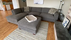 A living room with a gray sectional sofa, a small white tray, and a patterned throw pillow.