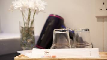 A tray with a tissue, a glass, and a bottle of water on a wooden surface.