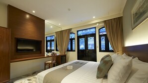 A hotel room with a large bed, a desk, a chair, and a TV mounted on the wall. - Macalister Terraces Hotel (George Town)