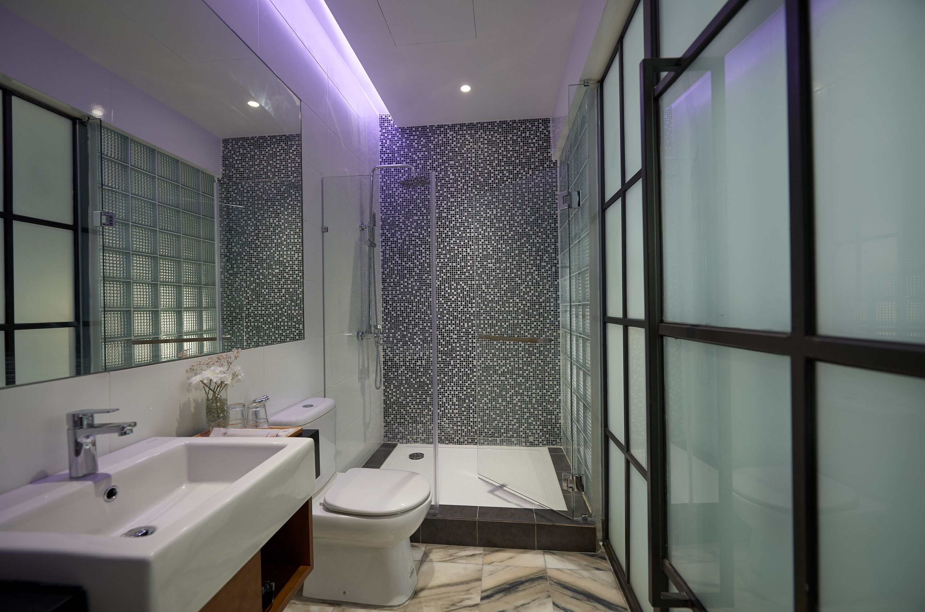 A modern bathroom with a large sink, toilet, and walk-in shower.