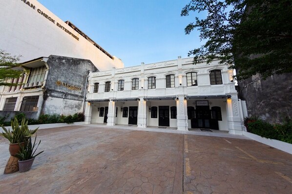 A building with a white facade, multiple doors, and a sign reading "Magalister." - Macalister Terraces Hotel (George Town)