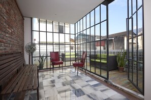 A spacious balcony with a checkered floor, a wooden bench, and red chairs. - Macalister Terraces Hotel (George Town)