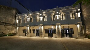 A historic building with a symmetrical facade, large windows, and a central entrance with a door and a small balcony. - Macalister Terraces Hotel (George Town)