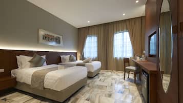 A hotel room with a large bed, a smaller bed, a desk, and a chair.