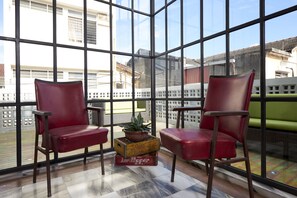 A modern room with large windows, two red chairs, a small table, and a potted plant. - Macalister Terraces Hotel (George Town)
