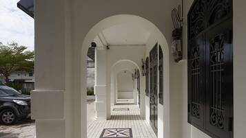 A corridor with white tiled flooring, black decorative doors, and a car parked outside.