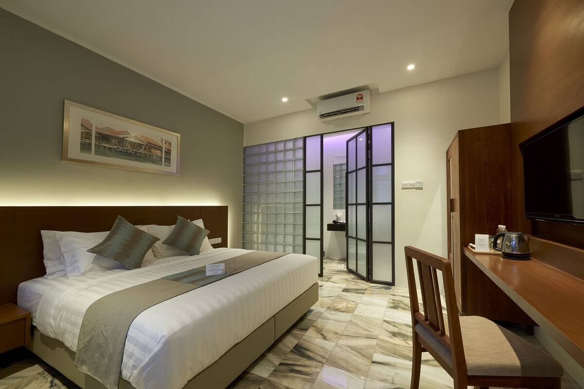 Habitación de hotel con una cama grande, televisión, escritorio y vista a través de una puerta de cristal.