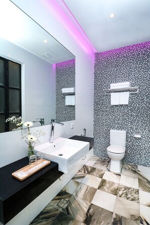 A modern bathroom with a white sink, black countertop, and a tiled floor with a marble pattern. - Macalister Terraces Hotel (George Town)