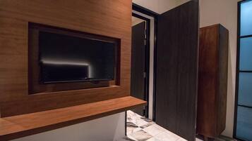A modern interior with a flat-screen TV mounted on a wooden wall, a dark sliding door, and a tiled floor.