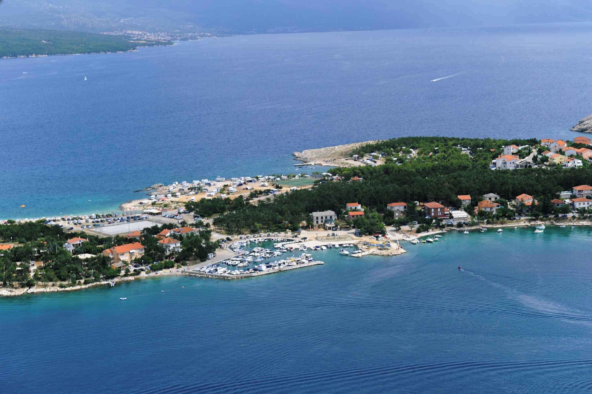 Eine Küstenstadt mit einem Yachthafen, Häusern und einem Strand.