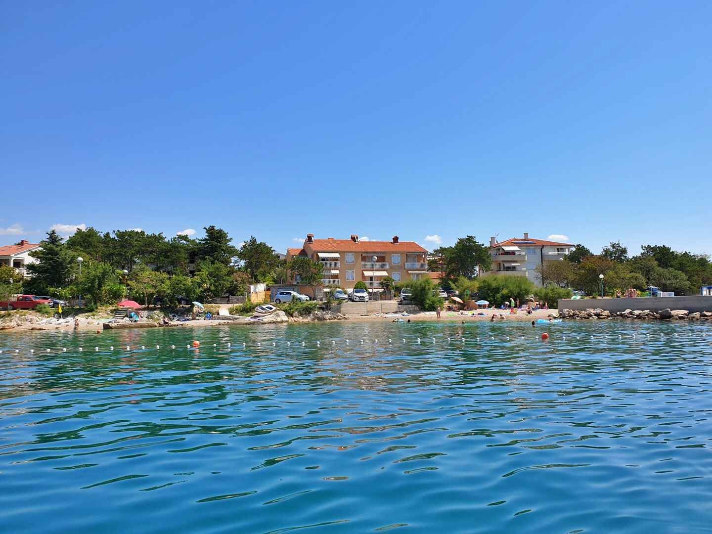 A waterfront property with a swimming pool, a beach, and a building with balconies.