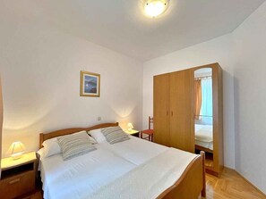 A bedroom with a bed, bedside lamps, a wardrobe, and a framed picture on the wall.