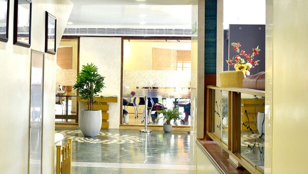 A hotel lobby with a marble floor, a large potted plant, and framed artwork on the walls. - The Senator Hotel (Kolkata)