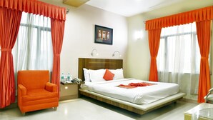A hotel room with a bed, a chair, a nightstand, and a picture on the wall. - The Senator Hotel (Kolkata)