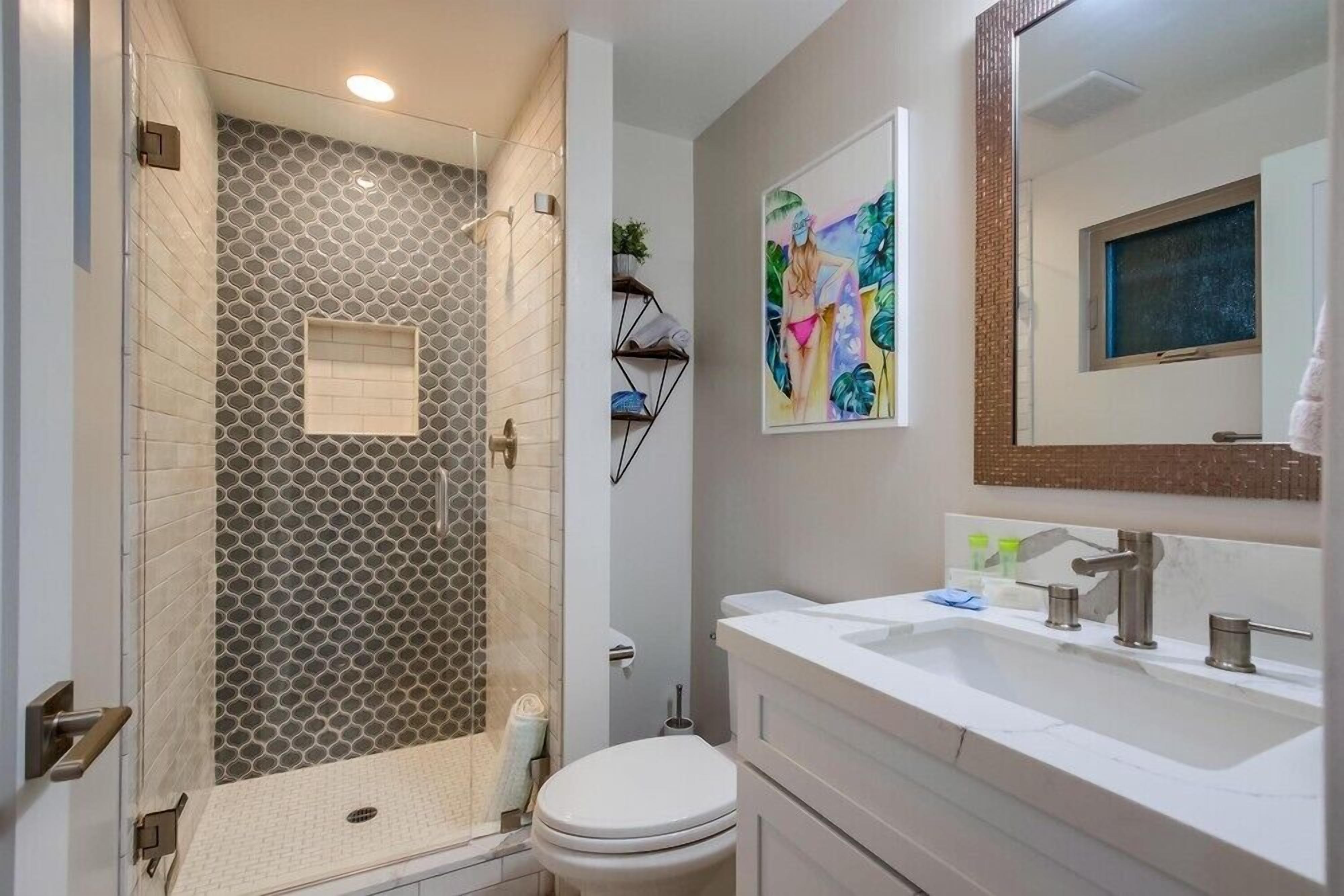 A modern bathroom with a shower, toilet, and vanity.