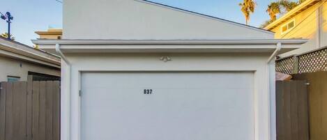 A garage with the number 837 on the door, surrounded by a wooden fence and a paved driveway.