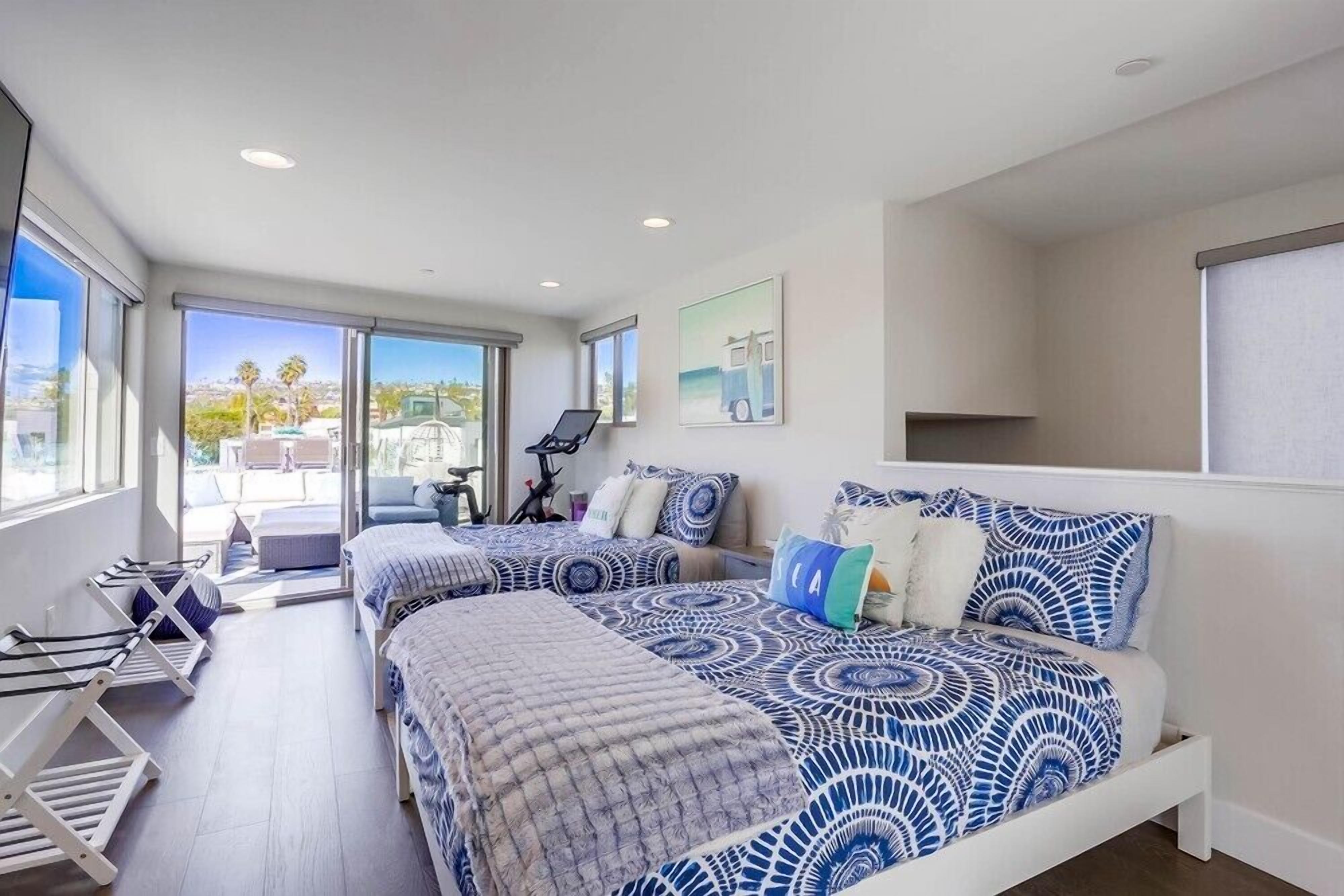 A modern bedroom with two beds, a large window, and a view of the outdoors.