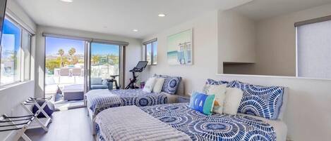 A modern bedroom with two beds, a large window, and a view of the outdoors.