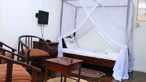 Un dormitorio con una cama con dosel, una mesita de noche, una silla y una pequeña mesa.