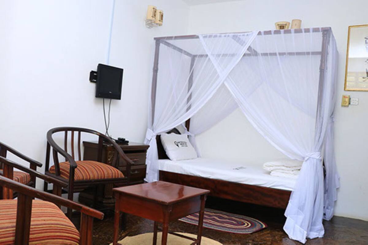 Un dormitorio con una cama con dosel, una mesita de noche, una silla y una pequeña mesa.