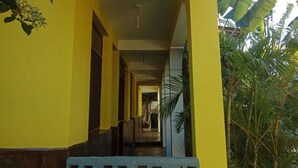 Un pasillo con paredes amarillas y un portón azul con diseño, que conduce a una escalera.