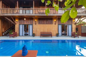 Un edificio de madera con piscina, bancos y plantas en macetas.