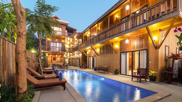 Zona de piscina con sillones de descanso y un edificio de madera con balcones.