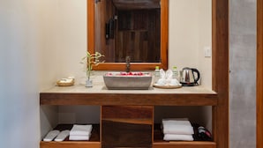 Un baño con tocador de madera, un espejo grande, un lavabo de piedra y un perchero para toallas.