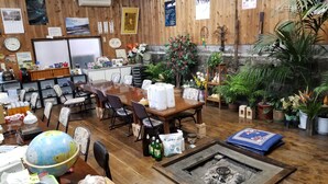 A wooden interior with a long dining table, chairs, a globe, and various potted plants. - Hachijojima Gardenso (Hachijo)