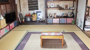 A traditional Japanese room with tatami flooring, a low wooden table, a television, and shelves with various decorative items. - Hachijojima Gardenso (Hachijo)