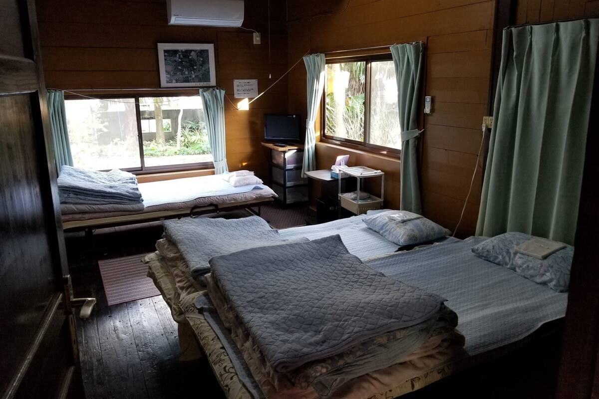 A cabin with two beds, a desk with a computer, and a window with curtains.