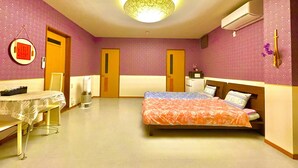 A hotel room with a bed, a desk, and a chair. There is a door, a wall-mounted air conditioner, and a wall decoration. - Inuyama Modern Room (Inuyama)