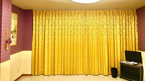 A room with a large yellow curtain, a ceiling light, a small black speaker, and a framed picture on the wall. - Inuyama Modern Room (Inuyama)